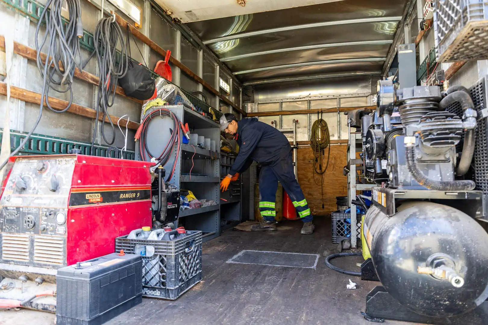 Big Rig Fixer technician organizing tools inside the mobile service truck, next to a welder and air compressor