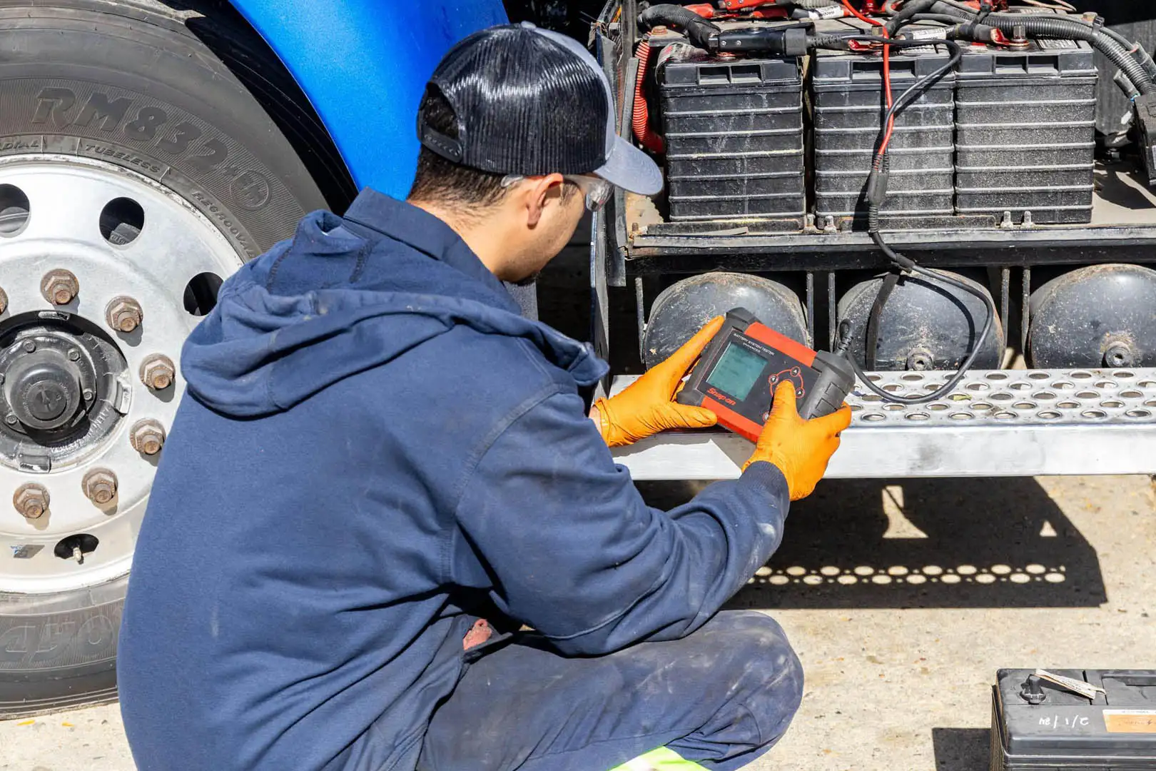 Technician testing truck batteries with device gloves