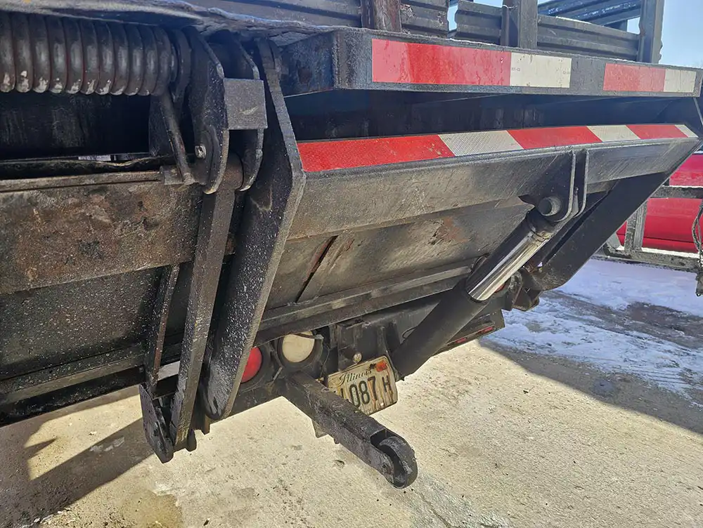 Technician servicing hydraulic and electrical components on a liftgate
